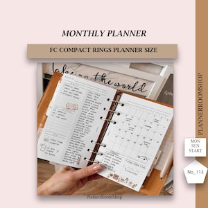 Puede incluir: Una agenda mensual blanca con una cubierta de cuero marrón. La agenda está abierta a una vista de calendario mensual y una lista de tareas. La agenda está etiquetada como "Planificador Mensual" y "Tamaño de agenda de anillos compactos FC".