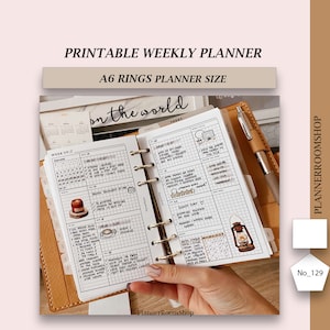 May include: A weekly planner with a brown leather cover and gold rings. The planner is open to a page with a grid layout and handwritten notes. The page is titled "on the world" and "TODAY". The planner is labeled "Printable Weekly Planner" and "A6 Rings Planner Size".