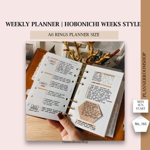 Puede incluir: Planificador semanal A6 estilo Hobonichi Weeks con anillas doradas. El planificador está abierto a una vista semanal, con notas manuscritas y una nota adhesiva. El texto en el planificador dice "WEEKLY PLANNER".