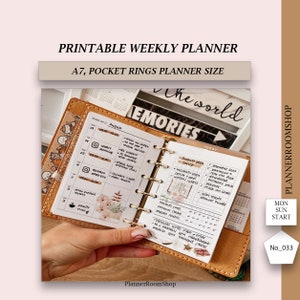 Op de afbeelding: Een close-up van een bruine leren A7-pocketplanner met een wekelijkse spreiding voor de week van augustus. De planner heeft een bloemenontwerp en de woorden "De Wereld" en "Herinneringen" staan op de omslag. De planner is open op een pagina met een wekelijks schema en een sectie voor "Augustusdoelen".