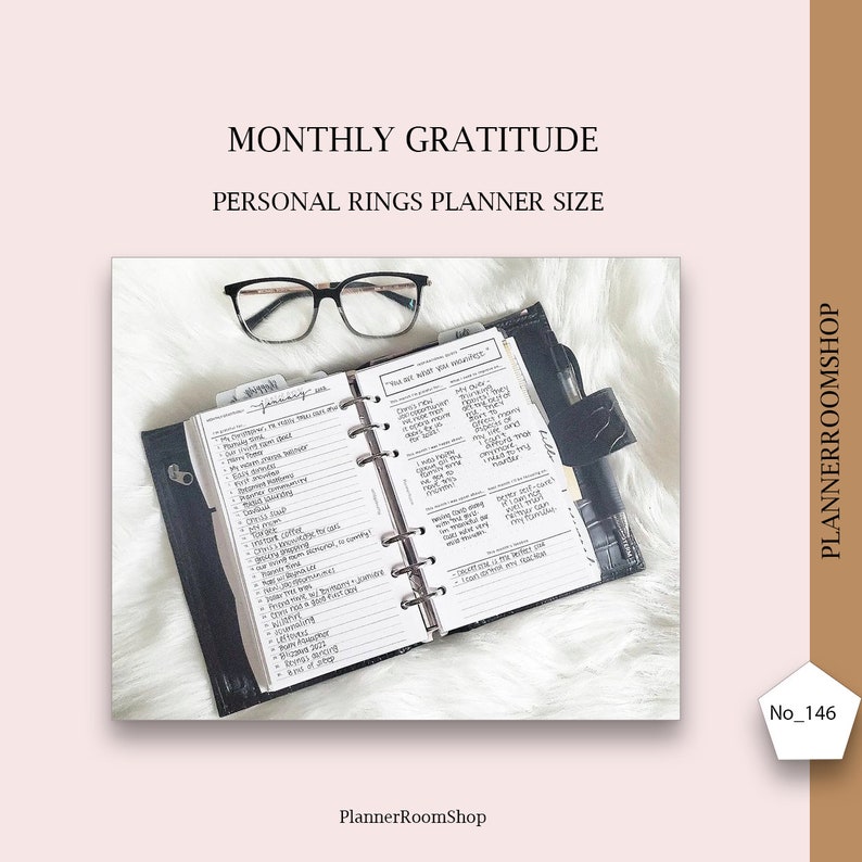 May include: A black and white planner with a monthly gratitude log. The planner is open to a page with a list of things to be grateful for. The planner is on a white fluffy surface with a pair of glasses on top of it.
