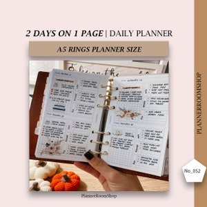 May include: A5 ring planner open to a daily spread. The planner pages are white with a grid pattern and handwritten notes. The cover is brown leather. The text on the top reads "2 DAYS ON 1 PAGE | DAILY PLANNER" and "A5 RINGS PLANNER SIZE".
