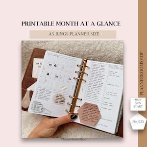 May include: A close-up of a brown leather A5 planner with gold rings. The planner is open to a monthly calendar page with handwritten notes and stickers. The text "PLANNERROOMSHOP" is printed on the bottom of the page.