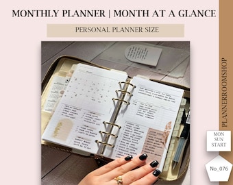 May include: Open monthly planner with gold rings, featuring a month-at-a-glance calendar and to-do lists. The planner is open to January, with handwritten notes and check marks. The text "MONTHLY PLANNER | MONTH AT A GLANCE" is visible.