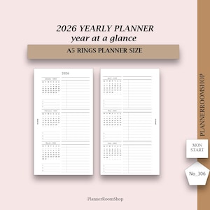 May include: A white 2026 yearly planner with a year-at-a-glance layout. The planner is A5 size and features monthly calendars and lined sections for notes. The text "2026 YEARLY PLANNER year at a glance A5 RINGS PLANNER SIZE" is displayed at the top.
