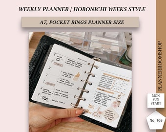 May include: A close-up of a black and white planner with a weekly agenda. The planner is open to the "Today" page, which features a to-do list and a section for notes. The planner is decorated with stickers and washi tape. The text "Don't worry be happy" is visible on a sticker. The planner is labeled "PlannerRoomShop".
