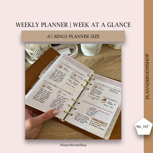 May include: A close-up of a brown leather A5 planner with gold rings. The planner is open to a weekly spread with a grid layout. The pages are filled with handwritten notes and stickers. The text "WEEKLY AGENDA" is visible at the top of the page.