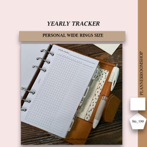 May include: A personal wide rings size planner with a brown leather cover, featuring a yearly tracker insert with a grid layout. The planner includes silver metal rings, tabbed dividers, and a white and brown pen held in a side loop.