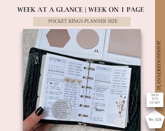 Puede incluir: Una agenda de bolsillo de cuero negro con una vista semanal abierta al mes de mayo. La agenda tiene un cierre de cremallera y está llena de notas escritas a mano y pegatinas. La agenda está etiquetada como "Week at a Glance | Week on 1 Page" y "Pocket Rings Planner Size".
