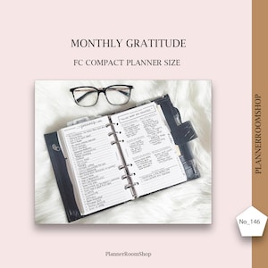 May include: A black FC compact planner with handwritten notes, open to a page with a list of items. The text "Monthly Gratitude" is at the top, with glasses resting above the planner. The planner is on a white, fluffy surface.
