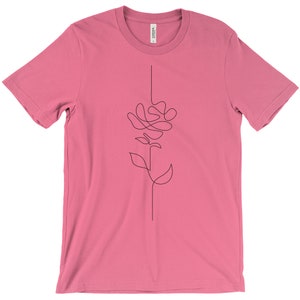 May include: A pink t-shirt featuring a single-line drawing of a rose on the front.