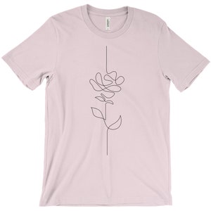 May include: A light pink t-shirt featuring a single-line drawing of a flower on the front.
