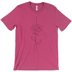 May include: A pink t-shirt featuring a black line drawing of a stylised rose on the front.