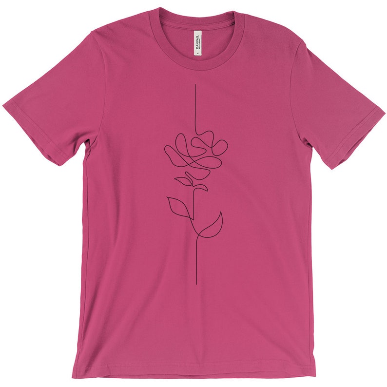 May include: A pink t-shirt featuring a black line drawing of a stylised rose on the front.