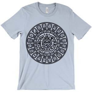 May include: A light blue t-shirt with a black Aztec calendar design printed on the front.