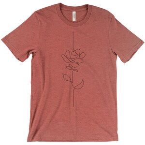 May include: A maroon t-shirt featuring a single-line drawing of a rose on the front.