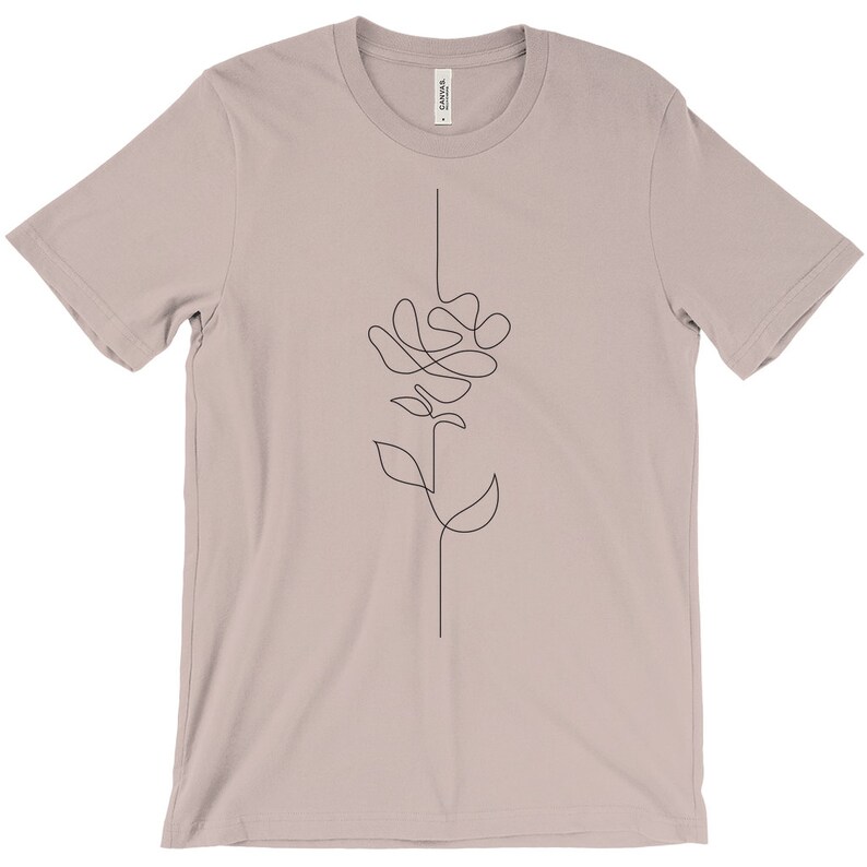 May include: A light pink t-shirt featuring a simple line drawing of a flower on the front.