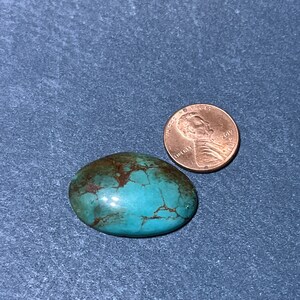 Puede incluir: Una piedra preciosa turquesa en cabuj&oacute;n con matriz marr&oacute;n, que mide aproximadamente el tama&ntilde;o de una moneda de un centavo de d&oacute;lar estadounidense.