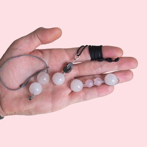 May include: Two necklaces with pink and white gemstone beads. One necklace has a silver clasp and a black cord. The other necklace has a gray cord and a silver clasp.