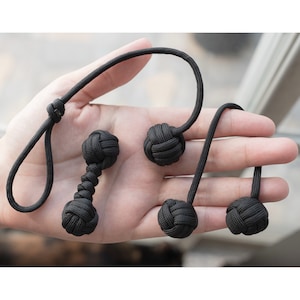 May include: Four black rope knots, two are tied together to form a dumbbell shape, and the other two are individual knots.