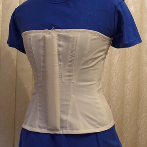 May include: A white corset with a front closure and a blue shirt underneath.