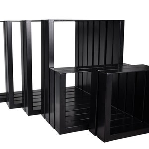 Può includere: Set di quattro gambe per tavolo in metallo nero con design quadrato. Le gambe sono impilate l'una sull'altra, con la gamba più grande in basso e la più piccola in alto.