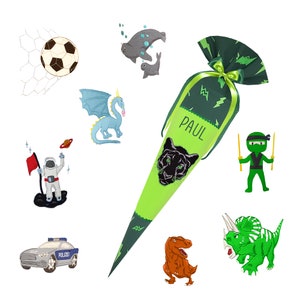 May include: A green and black school cone with the name "PAUL" printed on it. The cone is decorated with a black panther, lightning bolts, and a green bow. There are various illustrations around the cone, including a soccer ball, a dragon, a dinosaur, an astronaut, a ninja, and a police car.