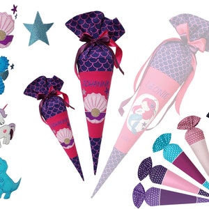 May include: A set of colorful school cones with mermaid and seahorse designs. The cones are decorated with glitter and have names embroidered on them, including "Leonie" and "Johanna".