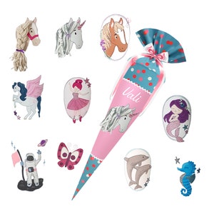 May include: A pink and blue cone-shaped party favor with white polka dots and a unicorn design. The cone is decorated with various colorful embroidered patches featuring a unicorn, a mermaid, a butterfly, a dolphin, a seahorse, a ballerina, and an astronaut. The cone has the name "Vali" written on it.