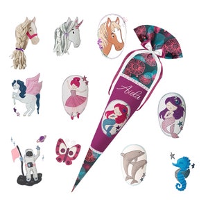 May include: A pink and purple school cone with the name "Aida" on it. The cone is decorated with a mermaid, a dolphin, a seahorse, a butterfly, a unicorn, a ballerina, and a horse.