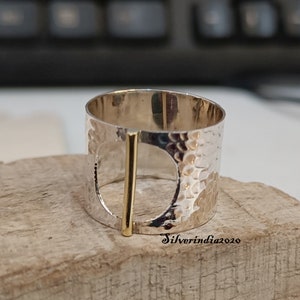 Puede incluir: Un anillo de plata con textura martillada y un acento de barra de oro. El anillo tiene un dise&ntilde;o de c&iacute;rculo abierto grande.