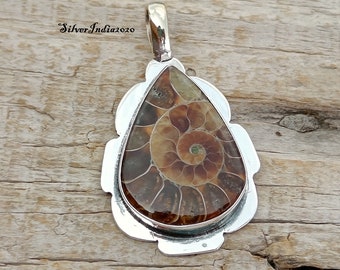 May include: A silver pendant featuring a teardrop-shaped ammonite fossil with brown and gold tones. The pendant has a detailed silver border and a bail for attaching a chain.