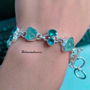 Puede incluir: Una pulsera de plata con una cadena y un cierre. La pulsera tiene varias piedras turquesa y azul claro.