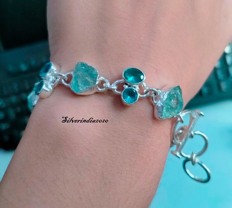 Puede incluir: Una pulsera de plata con una cadena y un cierre. La pulsera tiene varias piedras turquesa y azul claro.