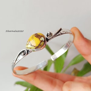 Op de afbeelding: Een zilveren manchetarmband met een druppelvormige, geel en bruine steen. De armband heeft een gehamerde textuur en decoratieve zilveren details. De tekst "Silverindia2020" is zichtbaar op de afbeelding.