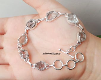May include: A silver bracelet featuring irregularly shaped, clear gemstones. The stones are linked together with silver chain and set in silver bezels. The bracelet has a toggle clasp. The text "Silverindia2020" is visible.