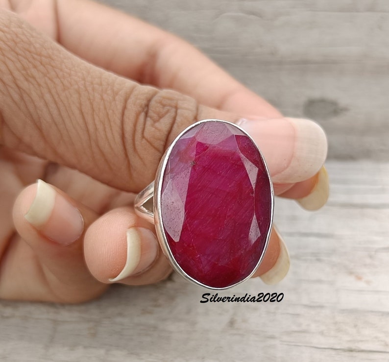 Pode incluir: Anel de prata com uma grande gema de rubi oval. O rubi &eacute; de um vermelho intenso e profundo. O anel &eacute; mostrado em uma m&atilde;o, destacando o tamanho e a cor da pedra preciosa.