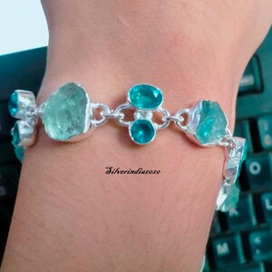 Puede incluir: Un brazalete de plata con un dise&ntilde;o de cadena y piedras preciosas azul aguamarina. El brazalete presenta varias piedras grandes de aguamarina de forma irregular y piedras redondas de aguamarina m&aacute;s peque&ntilde;as.