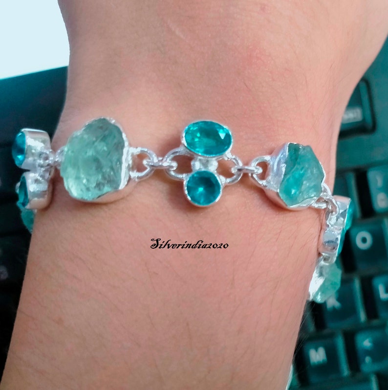 Puede incluir: Un brazalete de plata con un dise&ntilde;o de cadena y piedras preciosas azul aguamarina. El brazalete presenta varias piedras grandes de aguamarina de forma irregular y piedras redondas de aguamarina m&aacute;s peque&ntilde;as.