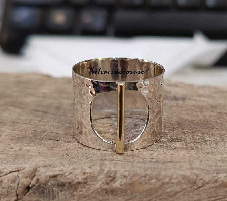 Puede incluir: Anillo de plata con textura martillada y una barra de oro en el centro. El anillo tiene un c&iacute;rculo grande abierto en el centro. El anillo est&aacute; grabado con el texto "Silverindia2020".