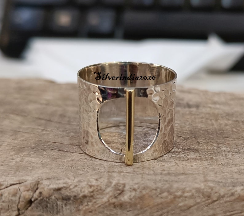 Puede incluir: Anillo de plata con textura martillada y una barra de oro en el centro. El anillo tiene un c&iacute;rculo grande abierto en el centro. El anillo est&aacute; grabado con el texto "Silverindia2020".