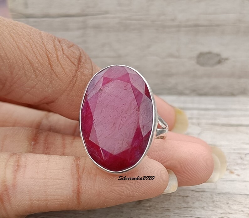 Pode incluir: Um anel de prata com uma grande pedra preciosa de rubi de corte oval. O rubi &eacute; de cor vermelha profunda e est&aacute; engastado numa banda de prata polida. O anel &eacute; uma pe&ccedil;a de joalharia marcante.