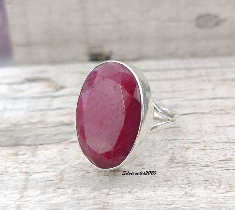 Pode incluir: Um anel de prata com uma grande gema de rubi de corte oval. O rubi tem uma cor vermelha profunda e est&aacute; engastado numa banda de prata polida. O design do anel &eacute; simples, real&ccedil;ando a beleza da gema.