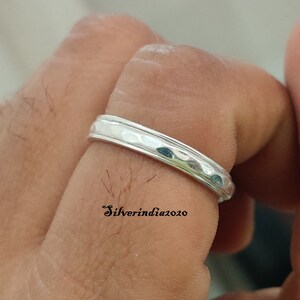 May include: A silver hammered band ring. The ring is worn on a finger.