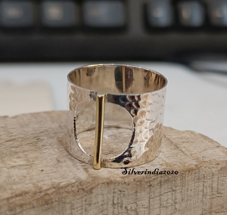 Puede incluir: Un anillo de plata con textura martillada y un acento de barra de oro. El anillo tiene un dise&ntilde;o de c&iacute;rculo abierto grande.