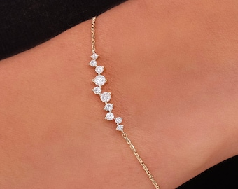 Puede incluir: Un delicado brazalete de cadena de oro con una línea curva de pequeños diamantes brillantes.