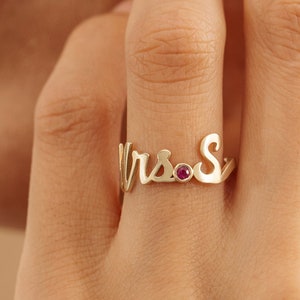 May include: Gold ring with the word "Mrs." and a small red gemstone.