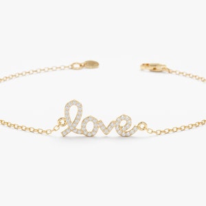 May include: A gold chain bracelet with a pave diamond 'LOVE' charm.