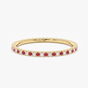 May include: A gold band ring with a row of alternating red rubies and white diamonds.