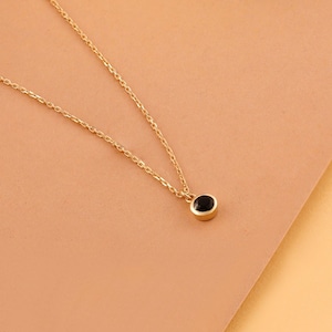 May include: A delicate gold chain necklace with a small black gemstone pendant.